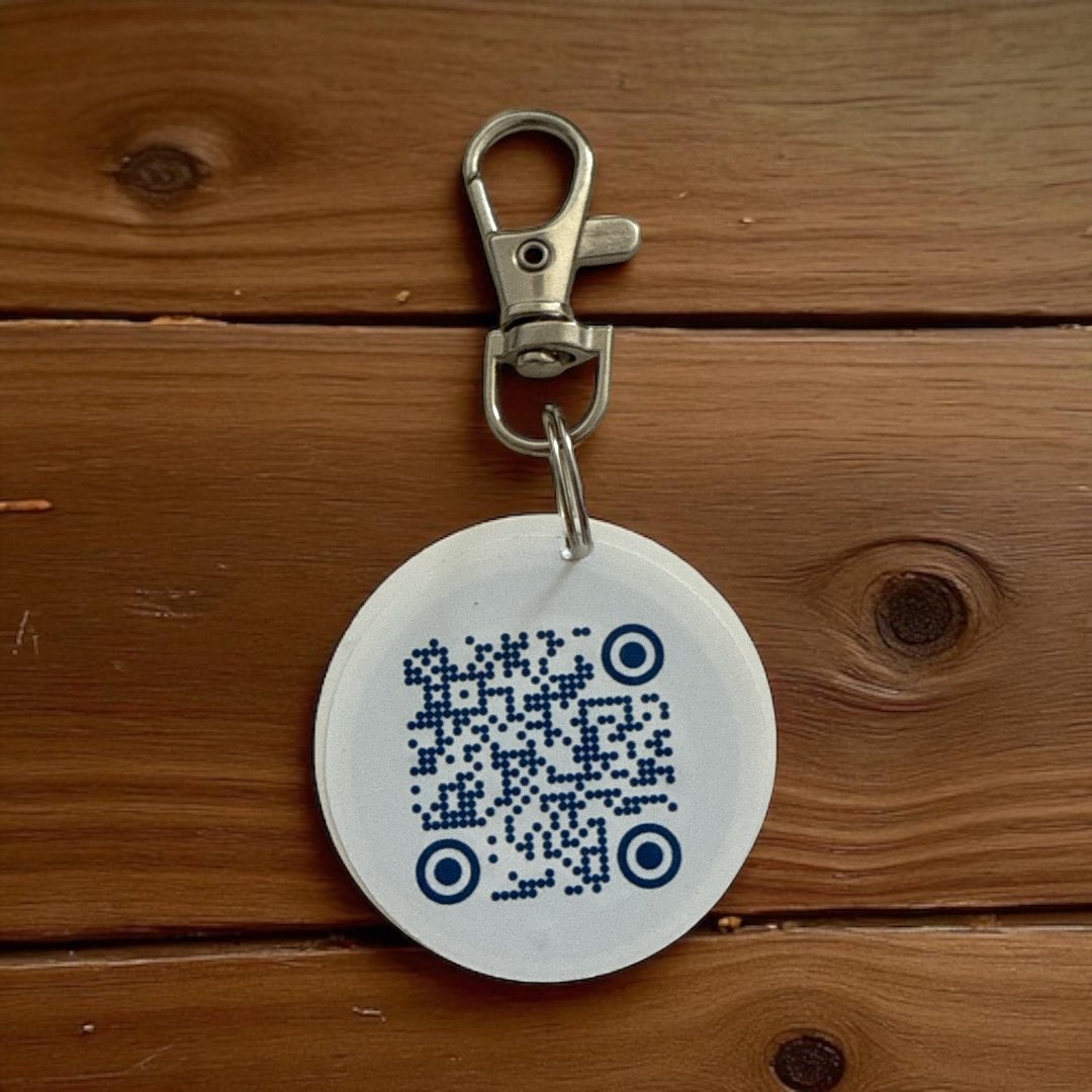 Badge rond blanc avec QR code bleu marine centré, fond bois foncé — variante QR Code